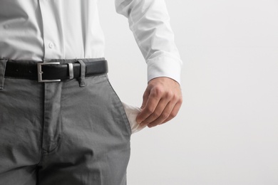Photo of Businessman showing empty pocket on light background, closeup. Space for text