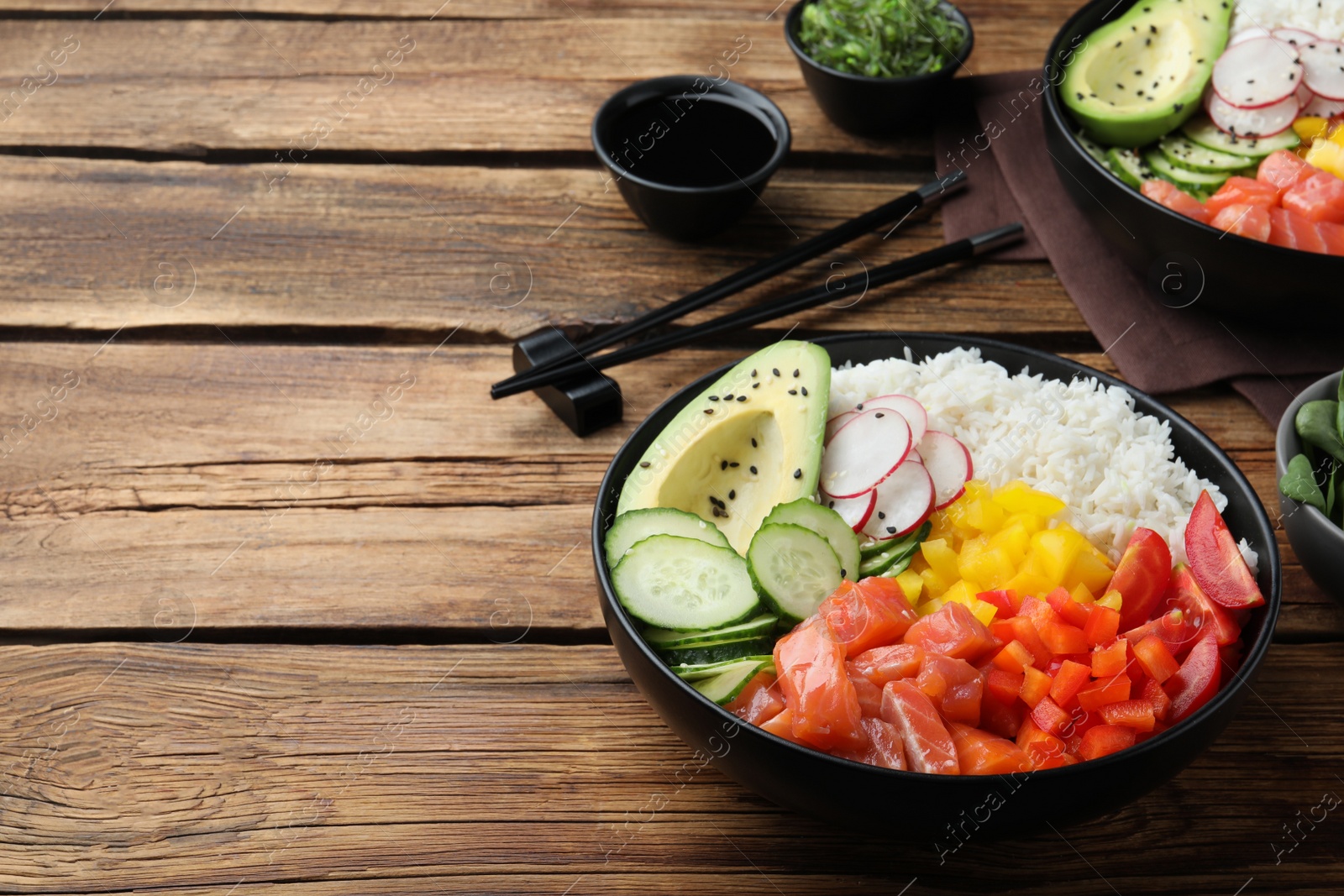 Photo of Delicious poke bowl with salmon and vegetables served on wooden table. Space for text