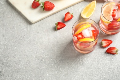 Photo of Tasty refreshing drink with strawberries and lemon on light grey table, above view. Space for text