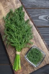 Photo of Bunch of fresh dill on black wooden table, top view