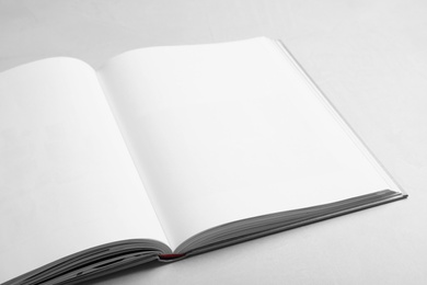 Photo of Open book with hard cover on light grey table, closeup