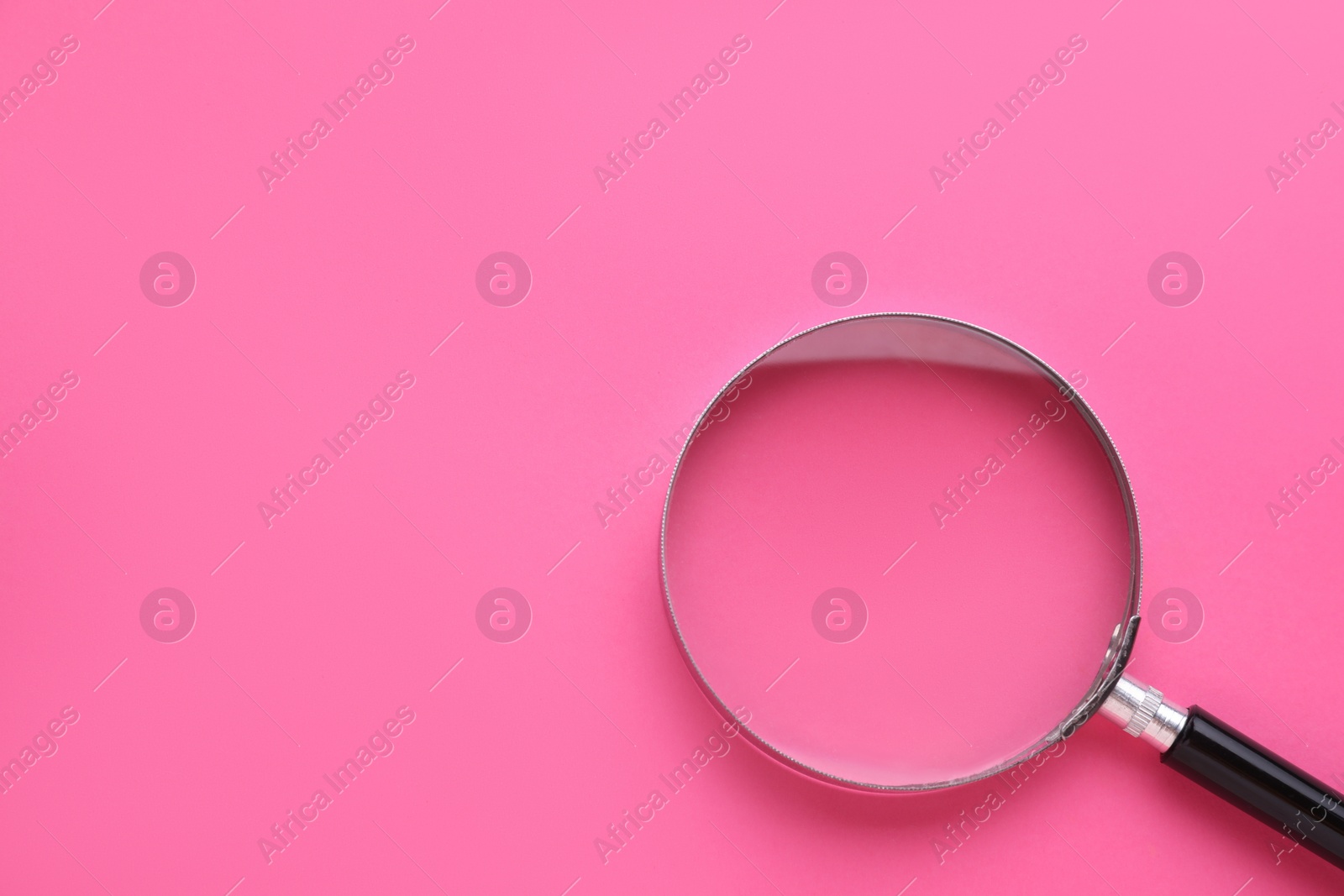 Photo of Magnifying glass on pink background, top view. Space for text