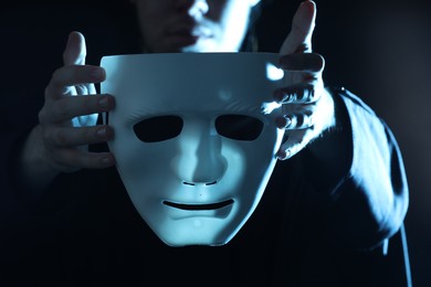 Photo of Theatrical performance. Man with plastic mask on dark background, closeup