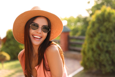 Image of Happy young woman with sunglasses and hat outdoors