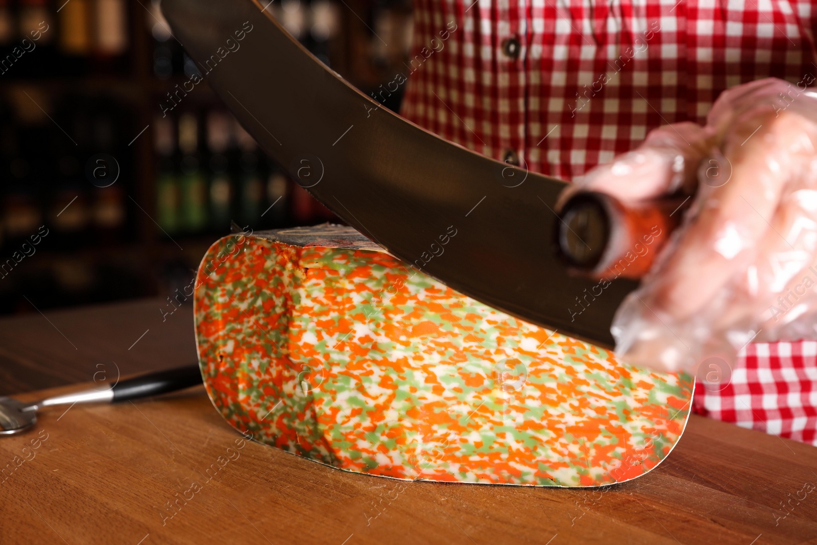 Photo of Seller cutting delicious cheese on table in store