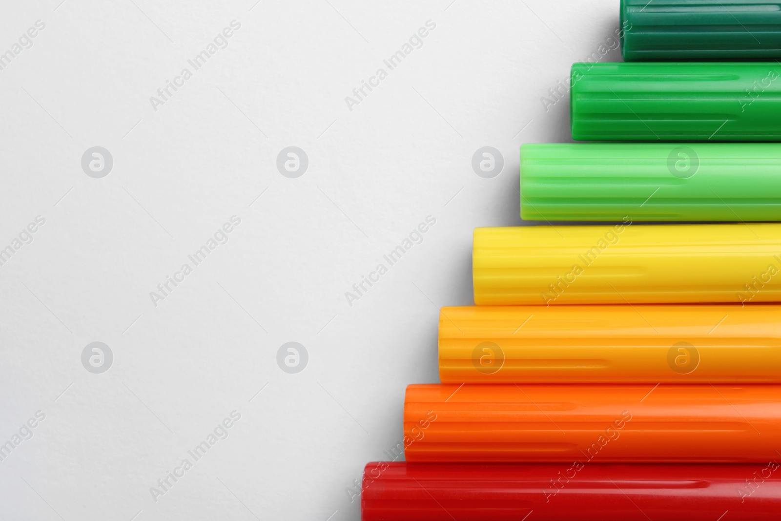 Photo of Flat lay composition with colorful markers on white background. Energy efficiency concept