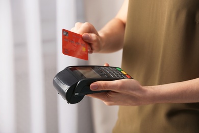 Woman using modern payment terminal indoors, closeup