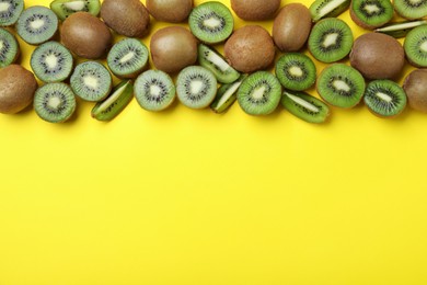 Photo of Many cut and whole fresh ripe kiwis on yellow background, flat lay. Space for text