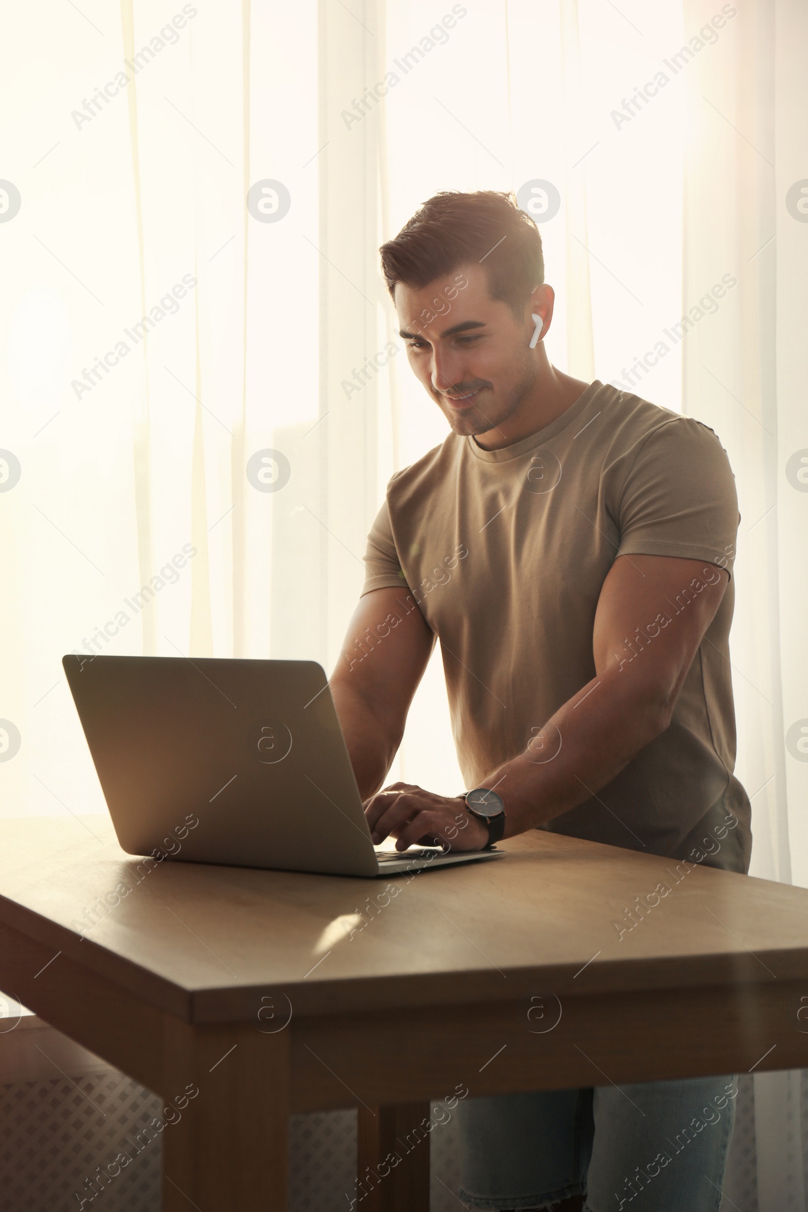 Photo of Portrait of young man with laptop at table indoors