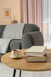 Photo of Books and cup of coffee on wooden table in living room, space for text