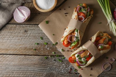 Photo of Delicious pita wraps with meat and vegetables on wooden table, flat lay. Space for text