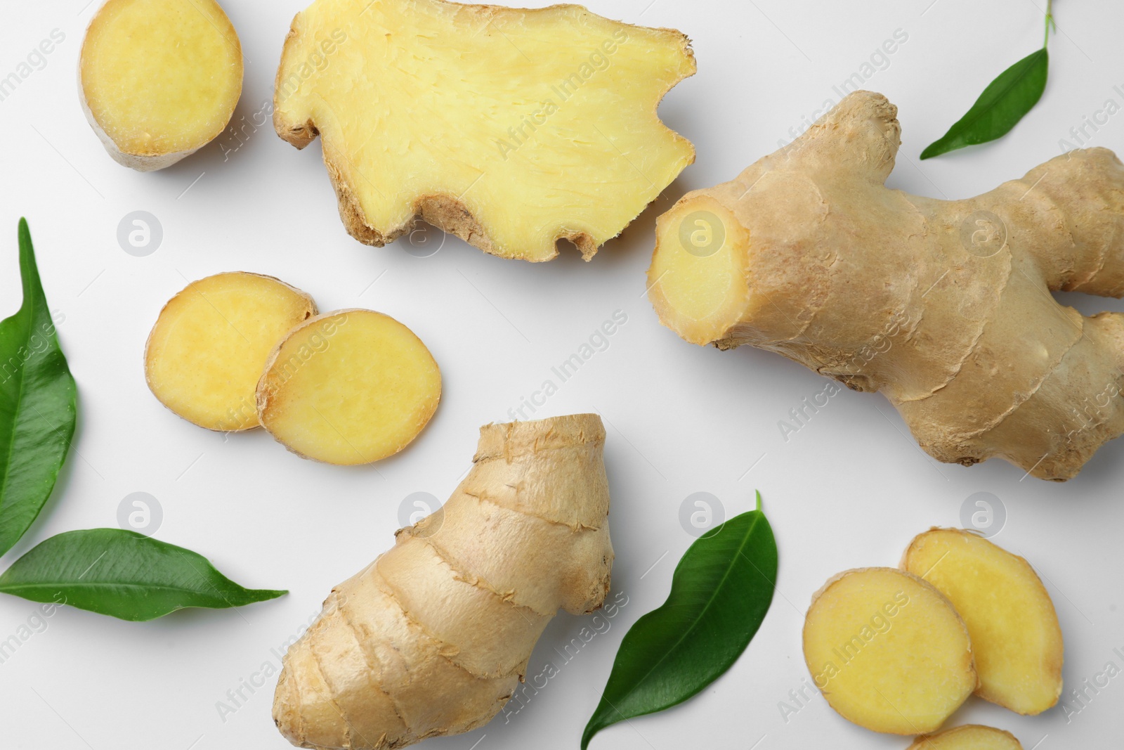 Photo of Fresh ginger with green leaves on white background, flat lay