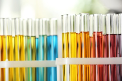 Photo of Test tubes with color liquids on blurred background, closeup view