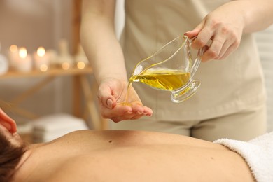 Photo of Aromatherapy. Woman receiving back massage with oil in spa salon, closeup