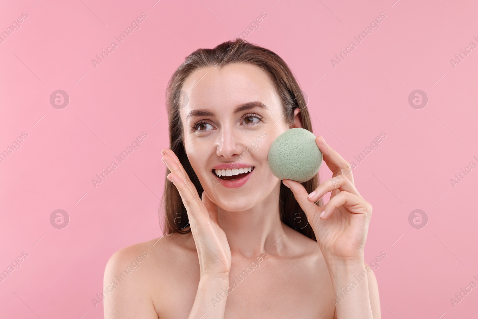 Photo of Happy young woman with face sponge on pink background