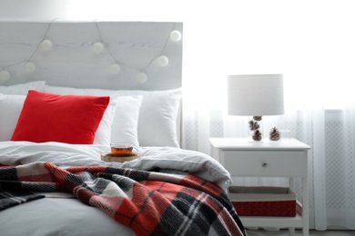 Comfortable bed with warm checkered plaid in stylish room interior