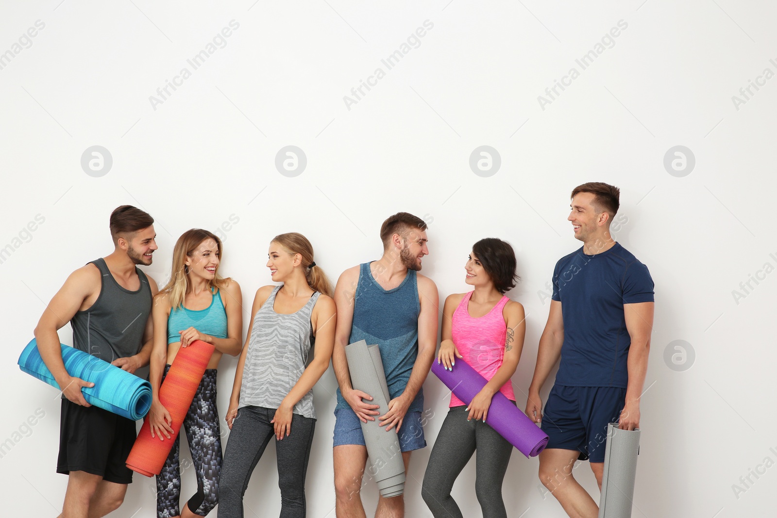 Photo of Group of young people waiting for yoga class on light background