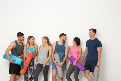 Photo of Group of young people waiting for yoga class on light background