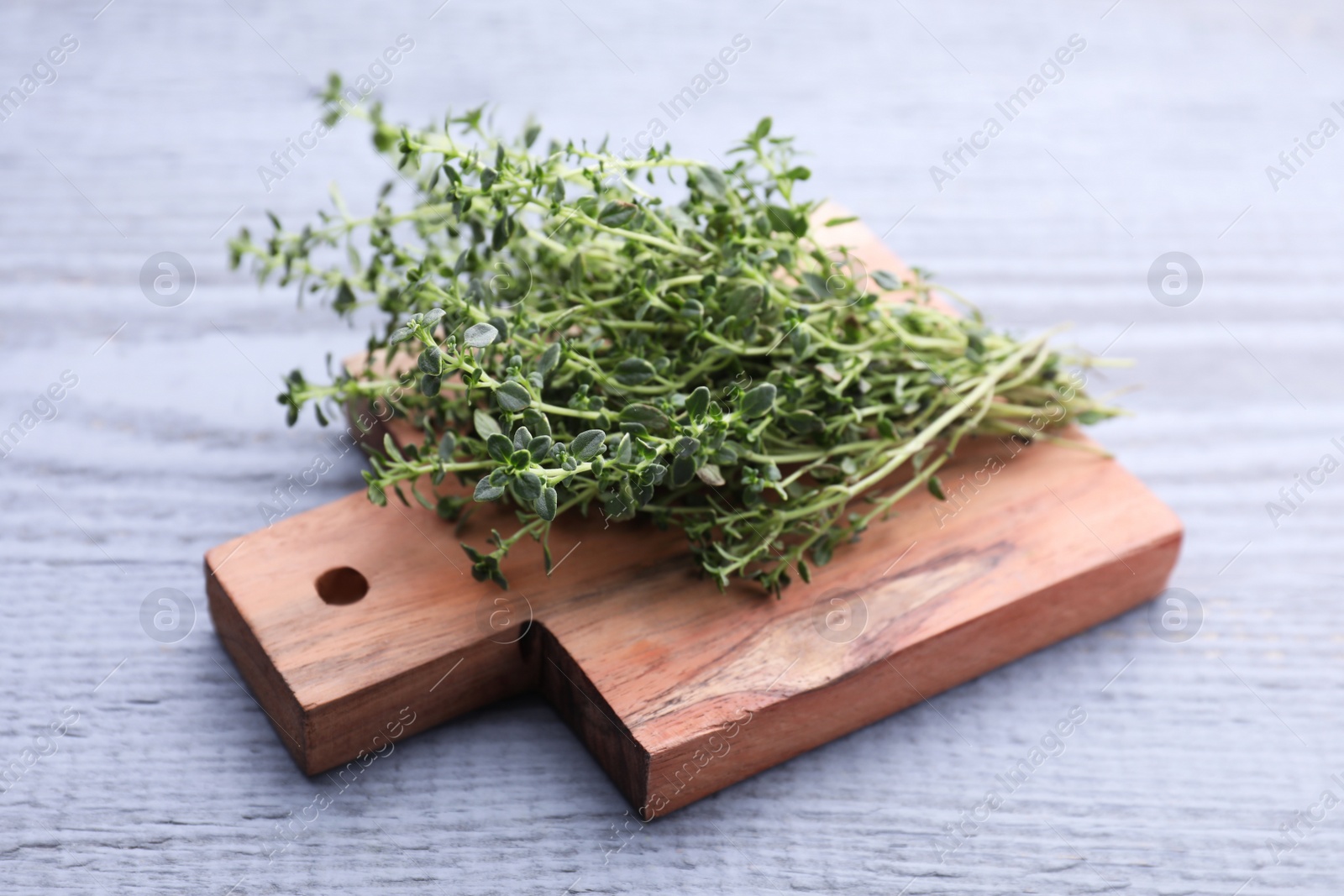 Photo of Bunch of aromatic thyme on light grey wooden table, closeup