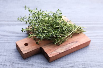 Photo of Bunch of aromatic thyme on light grey wooden table, closeup