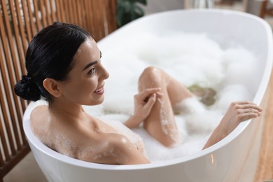 Beautiful young woman taking bubble bath at home