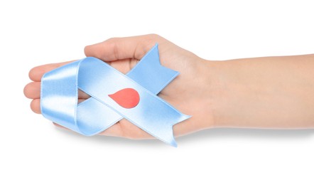 Photo of Woman holding light blue ribbon with paper blood drop on white background, top view. World Diabetes Day