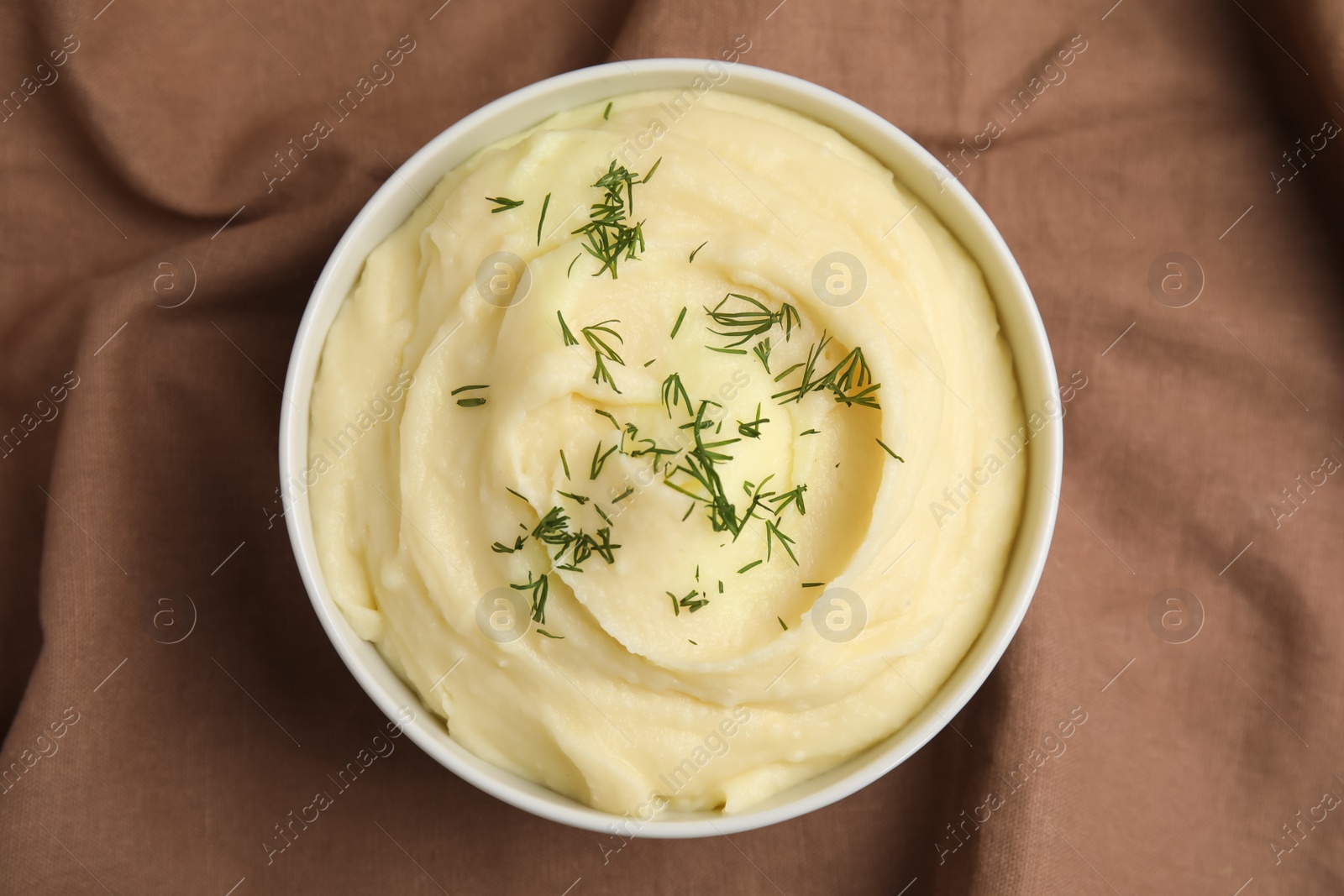 Photo of Freshly cooked homemade mashed potatoes on brown fabric, top view