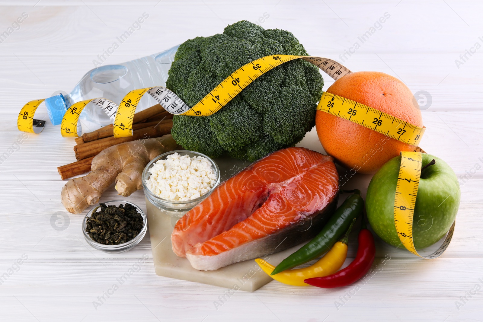 Photo of Metabolism. Different food products and measuring tape on white wooden table