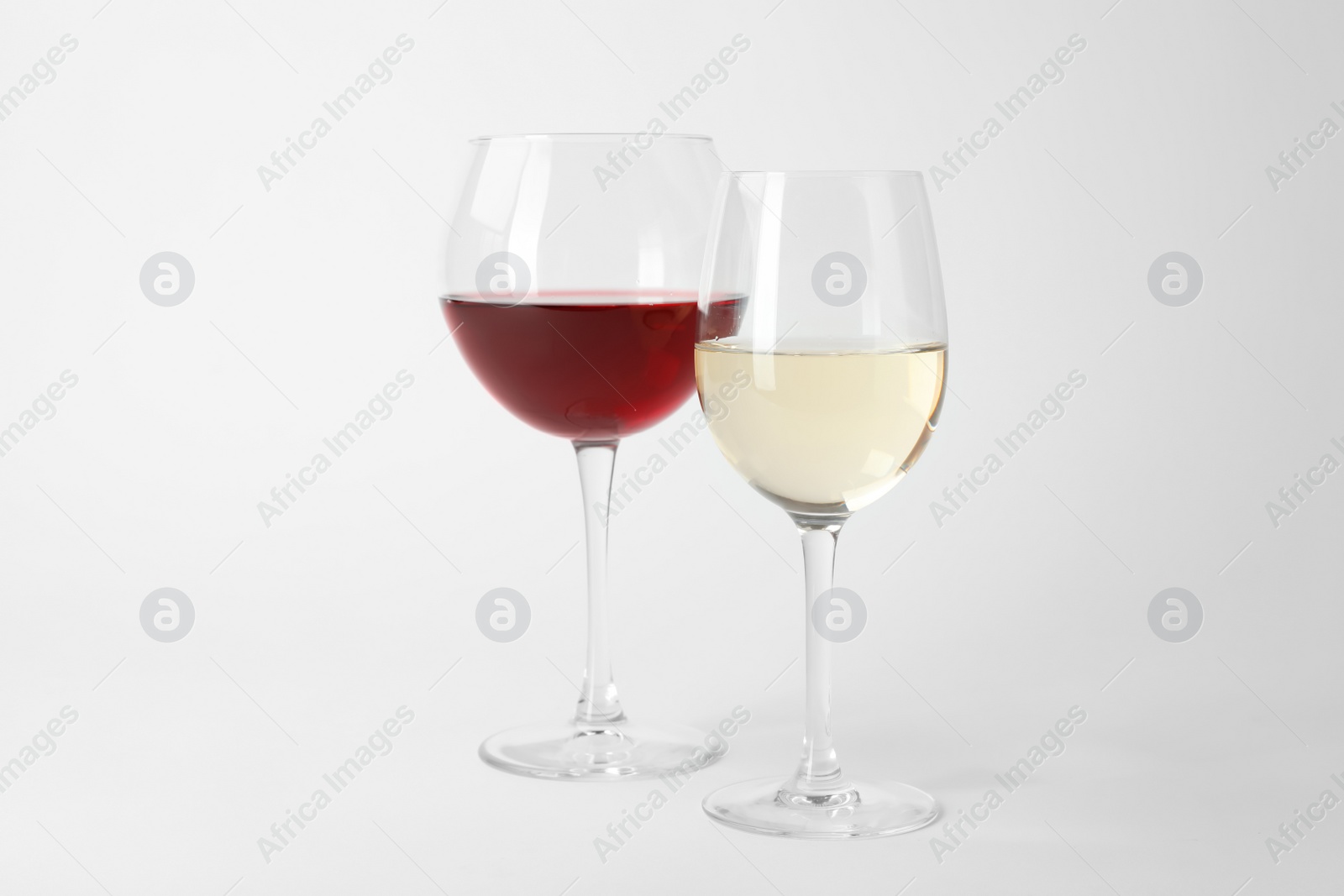 Photo of Glasses of expensive red and white wines on light background