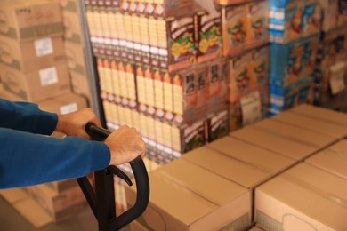 Image of Worker with pallet jack at warehouse, closeup. Logistics center