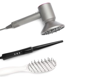 Image of Hair dryer, curling iron and brush on white background, top view