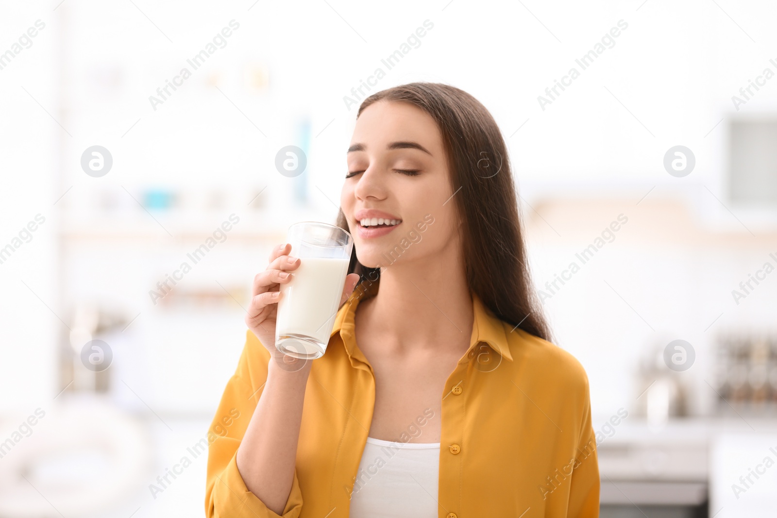 Photo of Beautiful young woman drinking milk at home