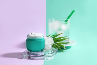 Photo of Cream with ice, green leaf and glass of cold drink on color background. Space for text