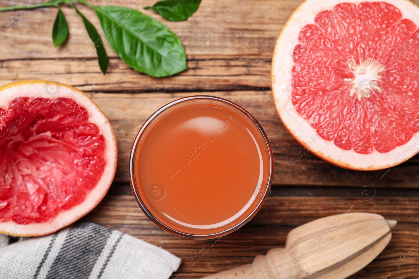 Photo of Tasty freshly made grapefruit juice and fruit on wooden table., flat lay