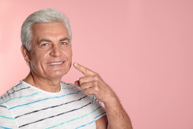 Mature man with healthy teeth on color background. Space for text