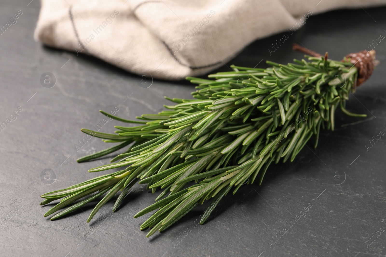 Photo of Bunch of fresh green rosemary on dark grey table, closeup