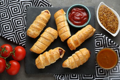 Delicious sausage rolls and ingredients on grey table, flat lay