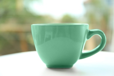 Photo of Mint green cup on table against blurred background