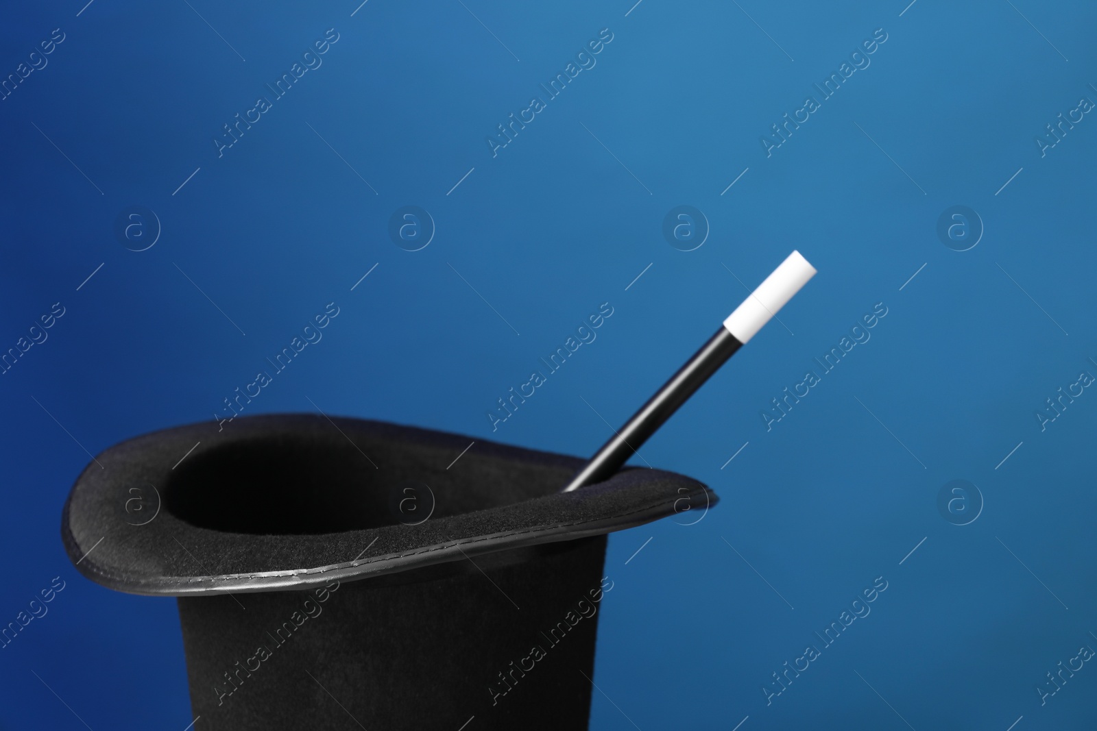 Photo of Magician's hat and wand on blue background