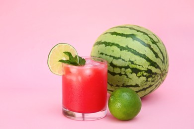 Photo of Glass of delicious watermelon drink with mint, lime and fresh fruits on pink background