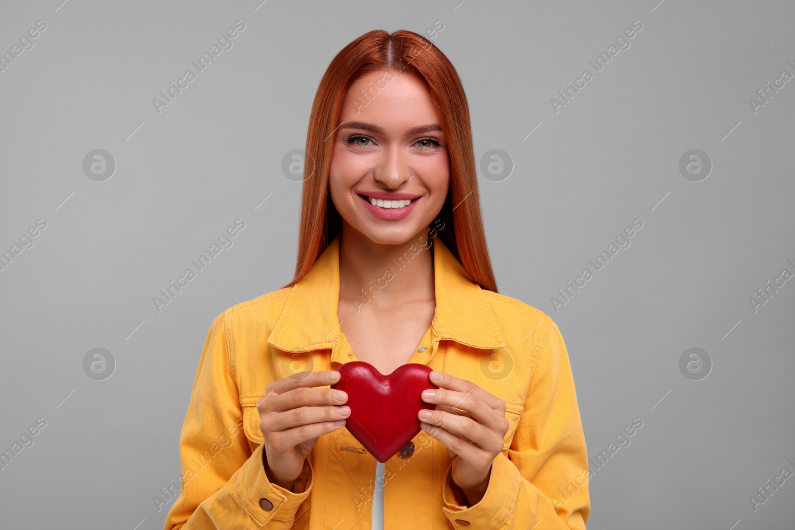 Photo of Beautiful happy woman with red heart on grey background