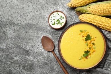 Delicious creamy corn soup served on grey table, flat lay. Space for text