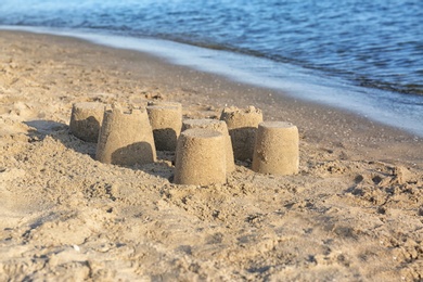 Photo of View of beach with little sand figures near sea on sunny summer day