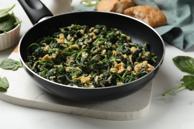 Photo of Tasty spinach dip with eggs in dish served on white table, closeup