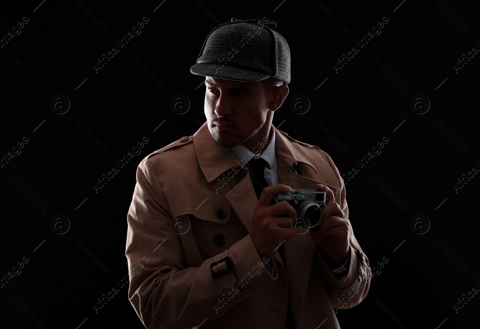 Photo of Old fashioned detective with camera on dark background