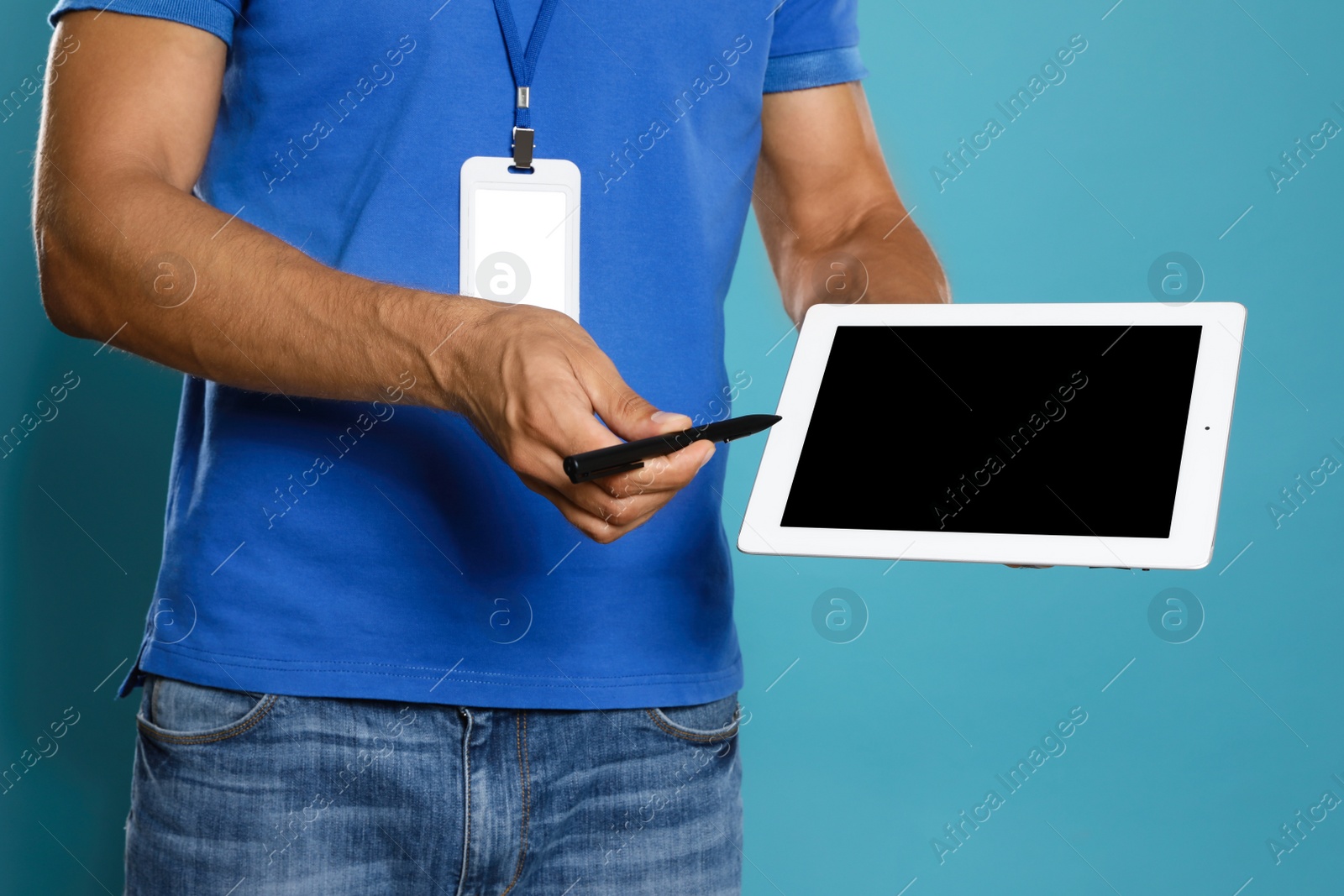 Photo of Young courier with tablet on blue background, closeup