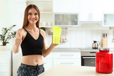 Photo of Young woman with bottle of protein shake in kitchen