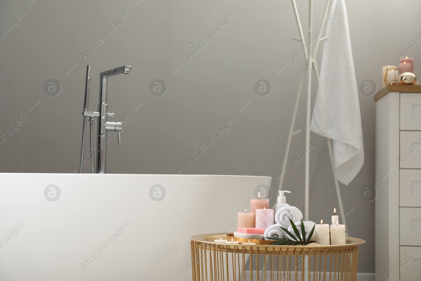 Photo of Stylish bathroom interior with ceramic tub and spa products on table