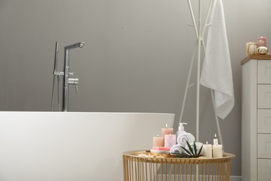 Photo of Stylish bathroom interior with ceramic tub and spa products on table