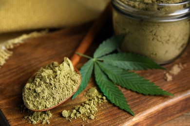 Hemp protein powder and fresh leaf on wooden board, closeup